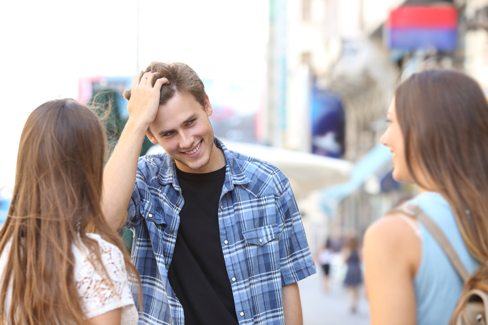 Handsome young man flirting with two girls in the street