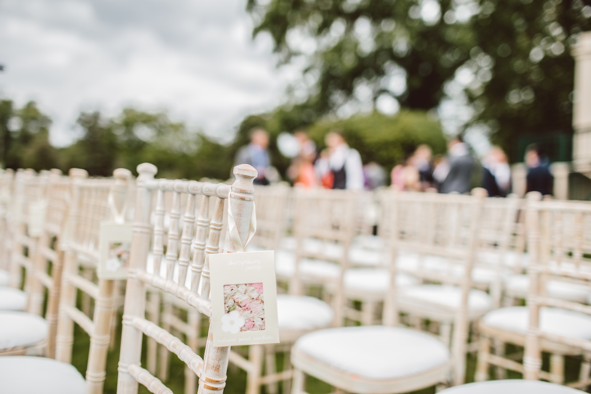White chairs at wedding ceremony and guests