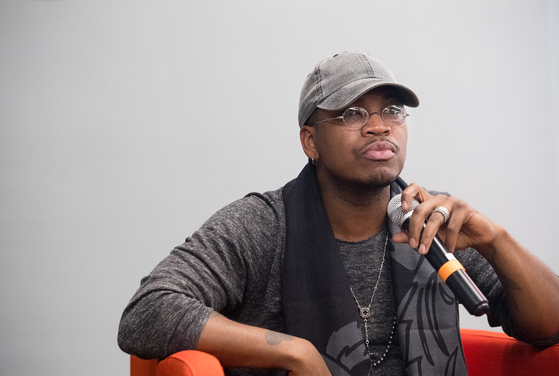 Ne-Yo wearing a grey shirt, hat and scarf